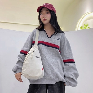 Modern grey polo sweatshirt paired with a minimalist cream nylon crescent crossbody bag