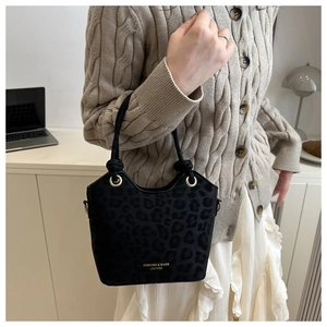 Detail of black leopard print suede tote bag with gold ring hardware and handles