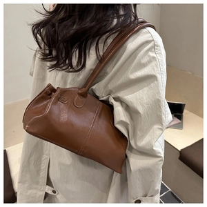 Brown vintage wax leather tote bag shown on model wearing light trench coat