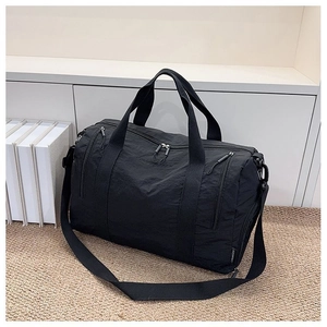 Close-up of black nylon travel bag with multiple zippers and durable woven shoulder strap