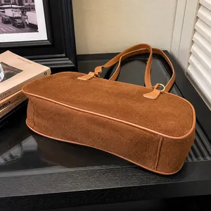 Detail of brown suede tote bag with slim leather straps and gold metal rings