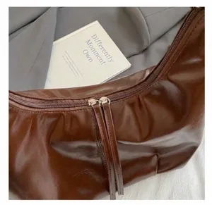 Detailansicht der braunen Tasche aus Ölwachsleder mit doppelten hellgoldenen Reißverschlüssen