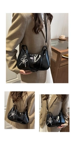 Detalle del bolso de media luna negro brillante con colgante de lazo plateado y correa