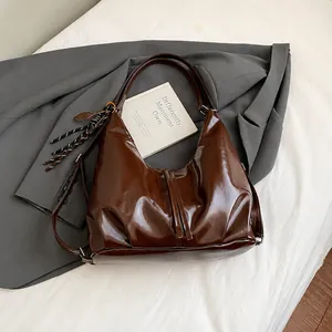 Détail du sac hobo en cuir brillant marron foncé avec pendentifs décoratifs uniques