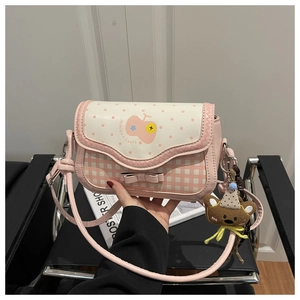 Detail van roze geruite crossbodytas met 3D-strik en een schattige teddybeer hanger
