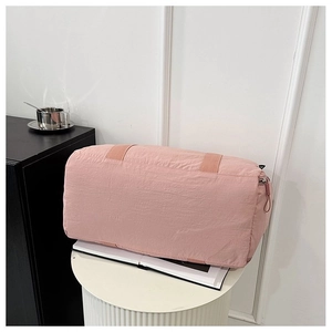 Detail view of pink nylon cylinder duffel bag with wide straps on a white display stand