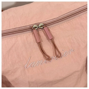Detail of pink nylon sports bag featuring dual zippers and embroidered logo text