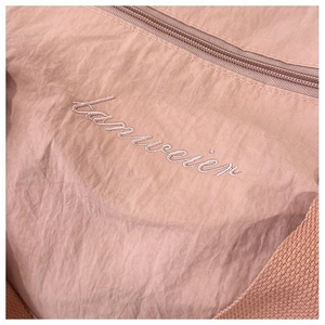 Close-up of nylon sports bag with pink embroidery and zipper detail in macro view
