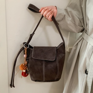 Sac à bandoulière en suède marron foncé avec surpiqûres et pendentif à pompon
