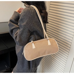 Detail shot of warm beige faux suede shoulder bag with white strap on model
