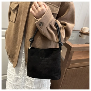 Detalle del bolso bombonera de ante negro minimalista con relieve decorativo