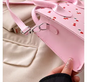 Detail van de zilveren metalen haak en D-ring op roze PU-leren tas met kersen