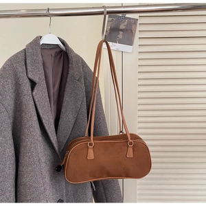 Detailed view of caramel suede baguette bag with zipper closure hanging on a hook