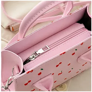 Detailoverzicht van de roze handtas met kersenprint en ritssluiting aan de bovenkant
