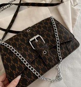 Detail show of brown monogram crossbody bag with silver chain strap and flap closure
