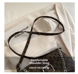 Detalle de la correa ajustable con monograma y hebilla plateada en un bolso bandolera marrón