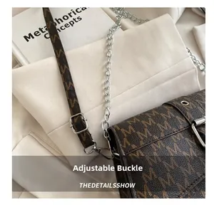 Detalle de la hebilla ajustable y cadena de un bolso bandolera con estampado monograma
