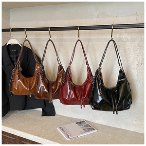 Détail de quatre sacs hobo en cuir brillant coloré avec bandoulières tressées et breloques