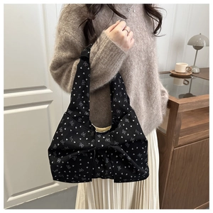 Detail of black bow-shaped handbag with white heart prints in a coquette style