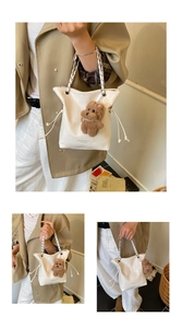 Detail of white glossy leather tote bag with drawstring, chain strap and bear charm