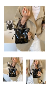 Detail of black glossy leather bucket bag with silver chain strap and plush bear charm