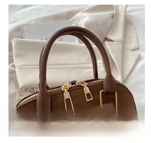 Close-up of dark brown suede handbag featuring dual zippers and sturdy leather handles