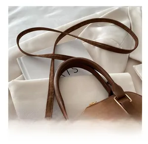 Detail of brown suede shell bag featuring gold hardware and adjustable strap