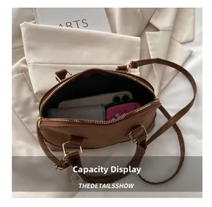 Interior capacity of the brown shell handbag with a phone, wallet, and golden zippers