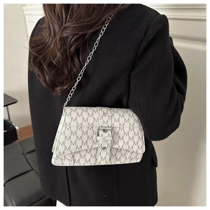 Detalle de bolso blanco con estampado de monograma M y cadena de metal plata