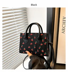 Detail of black cherry print square bag showing dual handles and detachable shoulder strap