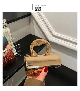 Detalle del bolso cilíndrico oro claro con asa artística de metal y cadena elegante