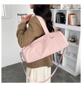 Close-up of pink nylon duffel bag featuring adjustable shoulder strap and metal hardware