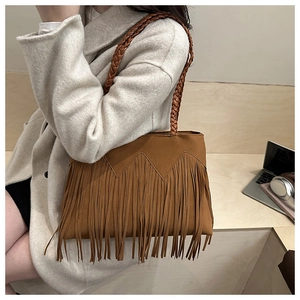 Close-up of caramel suede bucket bag featuring long tassels and woven shoulder strap details