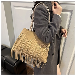 Detail of light brown fringe tote bag with braided handle shown on grey blazer outfit