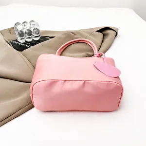Detail of the durable pink nylon handbag base with a heart charm on a white background