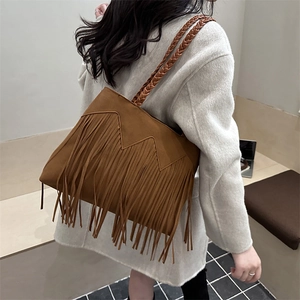 Brown suede bucket bag with long fringe tassels and woven shoulder straps in retro style