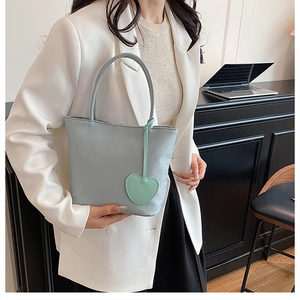 Detailed view of a mint green nylon tote bag with a heart charm in an office setting
