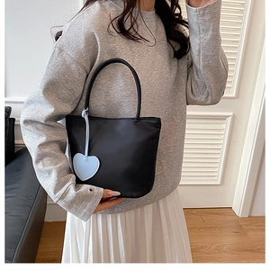 Mini black nylon handbag detail featuring a light blue heart-shaped pendant in a cozy room