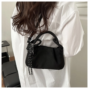 Detail of black pleated cloud bag with knotted handle and woven cord decoration