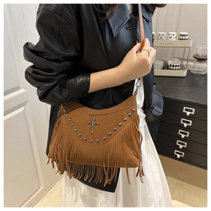 Détail du sac bandoulière en daim marron avec croix vintage, clous et longues franges