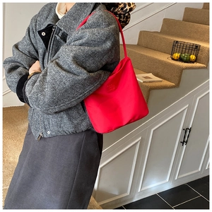 Nahaufnahme der hellroten Nylon-Schultertasche mit Logo-Prägung und elegantem Schulterriemen