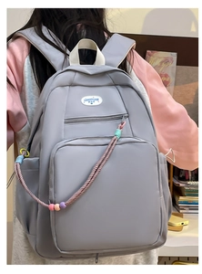 Dettaglio di uno zaino grigio per studenti con cordino intrecciato colorato sulla zip