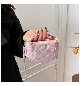 Detail van roze gewatteerde handtas met gouden camellasluiting en kettingriem