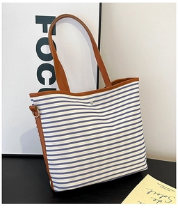 Detail der gestreiften Canvas-Tasche mit braunen Ledergriffen und D-Ring-Metallbeschlägen