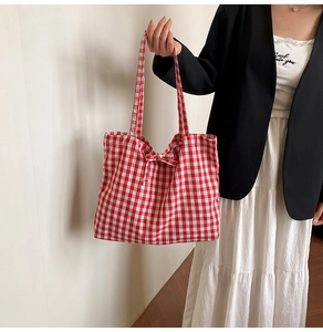 Detail of red checkered canvas tote bag with a bow decoration and long shoulder straps
