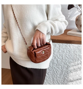 Detail van bruine gewatteerde crossbodytas met gouden bloemluiting en ketting