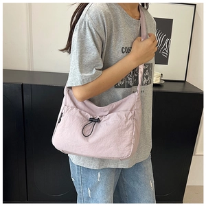 Détail d'un sac bandoulière lilas avec poche à cordon et fermoir noir en gros plan