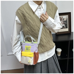 Model wearing a colorful patchwork Oxford fabric crossbody bag with a pixel heart patch
