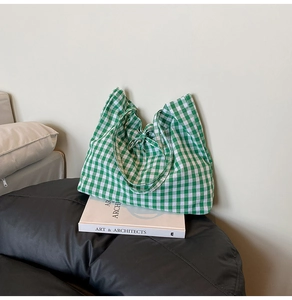 Detail of green and white gingham tote bag with tie-up closure on a casual leather seat