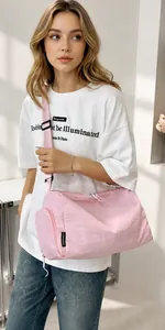 Pink nylon cylinder crossbody bag side view with adjustable strap and brand label